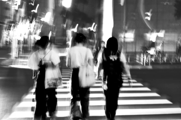 Blurred figures crossing under city lights.   -   Figuras borradas cruzando sob as luzes da cidade.